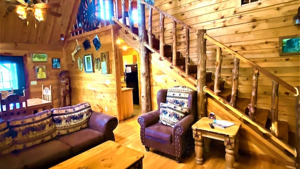 Un interior de madera con una escalera, un sofá y una mesa.
