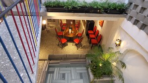 Un intérieur d’hôtel à plusieurs niveaux, avec un escalier, des chaises rouges, une table en bois et une plante en pot.