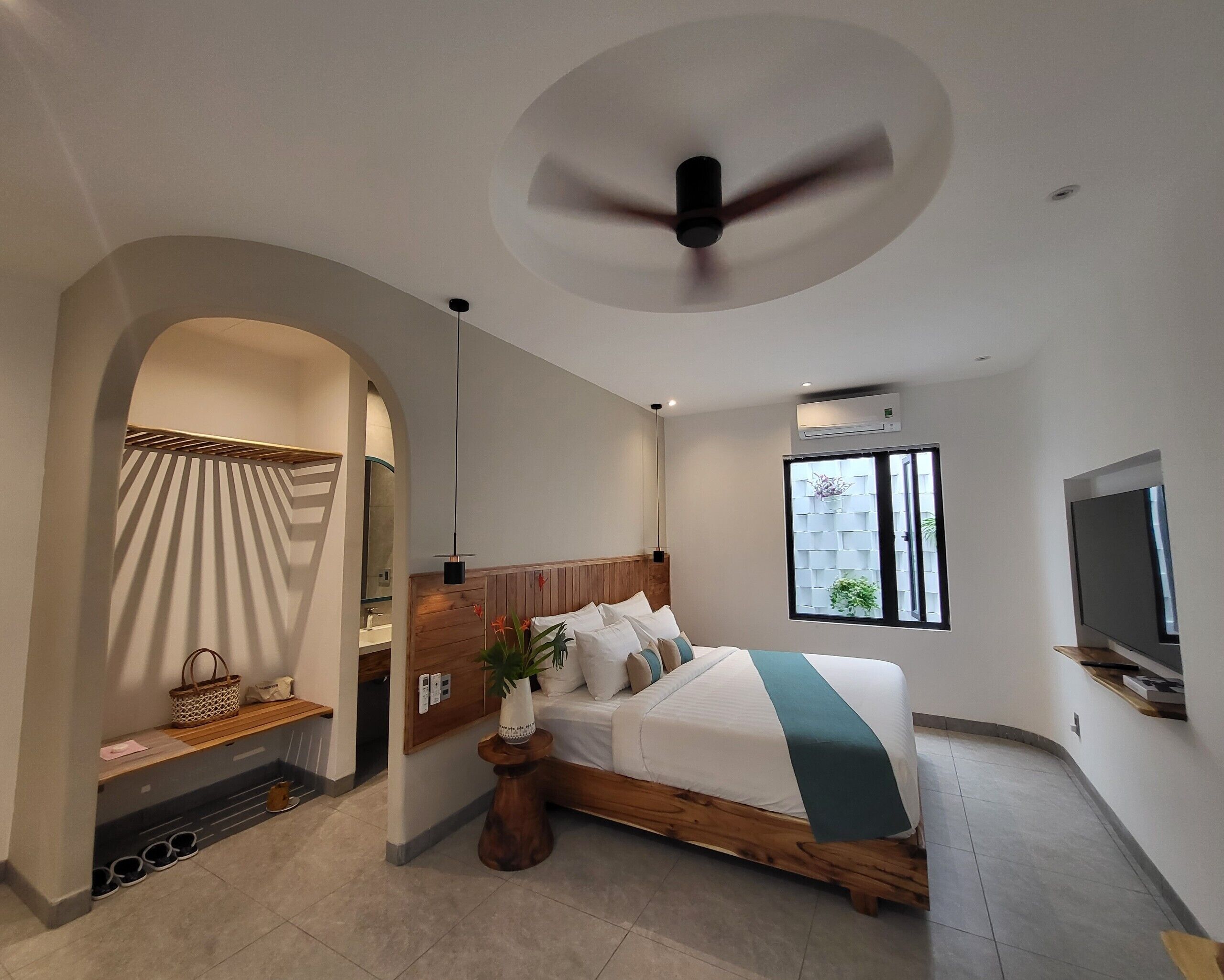 Un dormitorio moderno con una cama de madera, ventilador de techo, televisor y ventana con vistas.