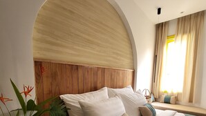 Une chambre d’hôtel avec un grand lit, une tête de lit en bois et une plante en pot.