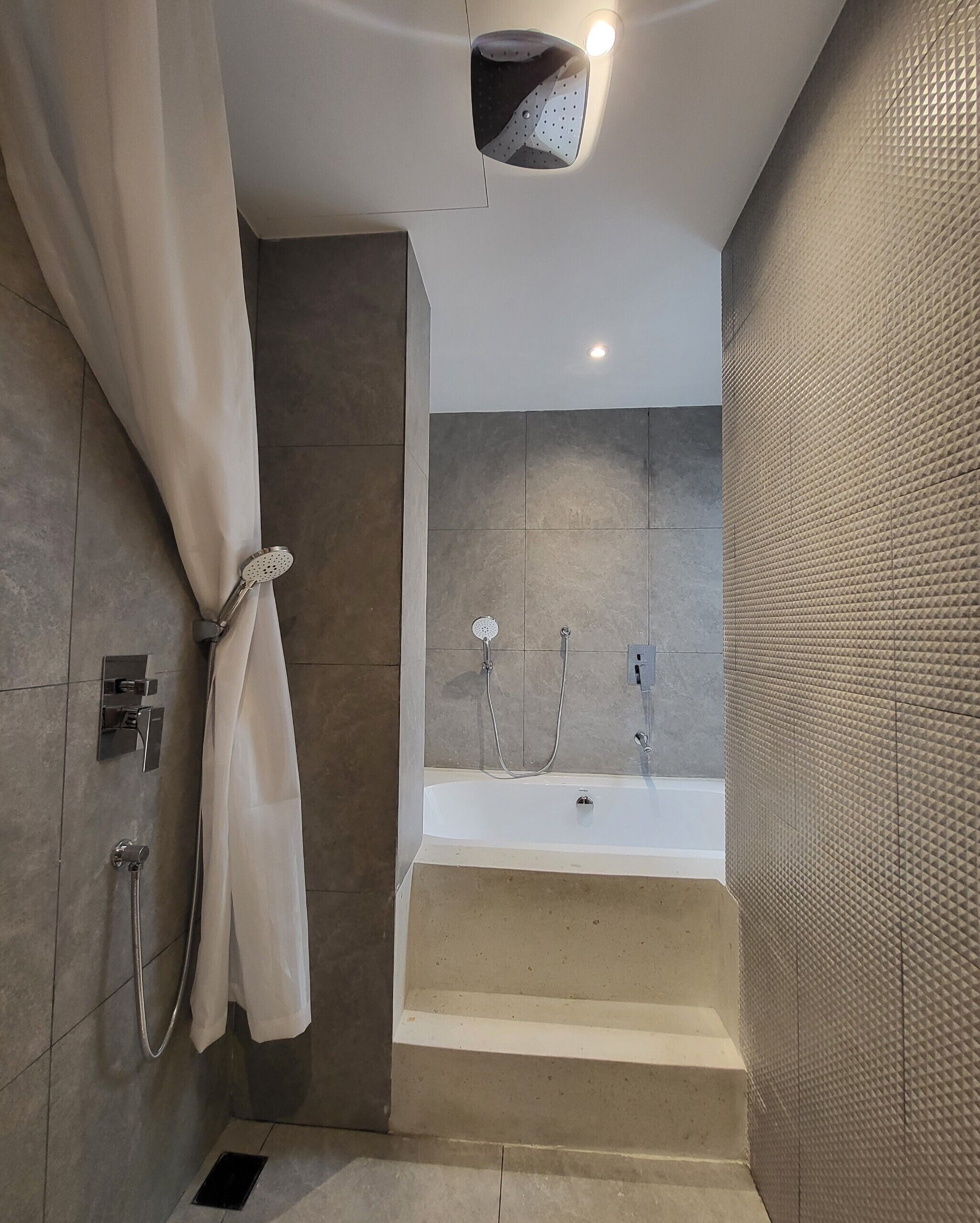 Un baño moderno con bañera, ducha y perchero para toallas.