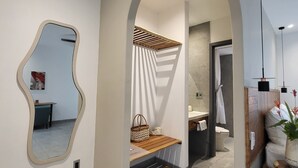 Une salle de bain moderne équipée d’une douche, d’un meuble-lavabo et d’un miroir à la forme originale.