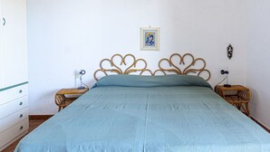 A bedroom with a bed, wooden headboard, two bedside tables, a nightstand, a wall-mounted picture, and a white dresser. - Carlotta, apartment a few steps from the pedestrian center of Marina di Campo equipped with air cond (Marina di Campo)