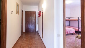 A narrow hallway with a wooden door at the end, a light switch, and a wall-mounted light fixture. - Carlotta, apartment a few steps from the pedestrian center of Marina di Campo equipped with air cond (Marina di Campo)
