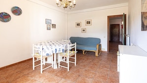 A dining area with a table and chairs, a blue sofa, and a chandelier. - Carlotta, apartment a few steps from the pedestrian center of Marina di Campo equipped with air cond (Marina di Campo)