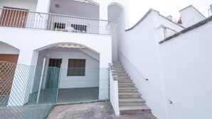 Un edificio bianco con un balcone, una scala e una recinzione in rete metallica.