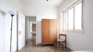 Una stanza con un letto, una sedia, un armadio e una scrivania.