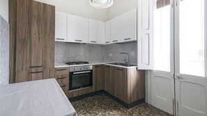 Una cucina compatta con mobili bianchi, un fornello a gas e un lavello.