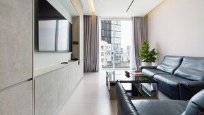 Un salon moderne avec un téléviseur à écran plat, un canapé en cuir, une table basse et une plante en pot.