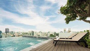 Un espace piscine aménagé sur le toit, avec des chaises longues et une vue sur la ville.