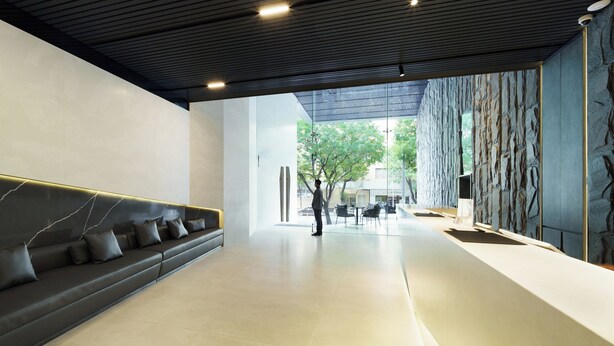 Un hall d’entrée moderne avec un canapé en cuir foncé, un mur décoratif en pierre et une vue sur l’extérieur.