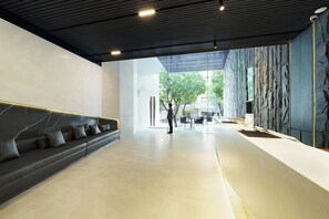 Un hall d’entrée moderne avec un canapé en cuir foncé, un mur décoratif en pierre et une vue sur l’extérieur.