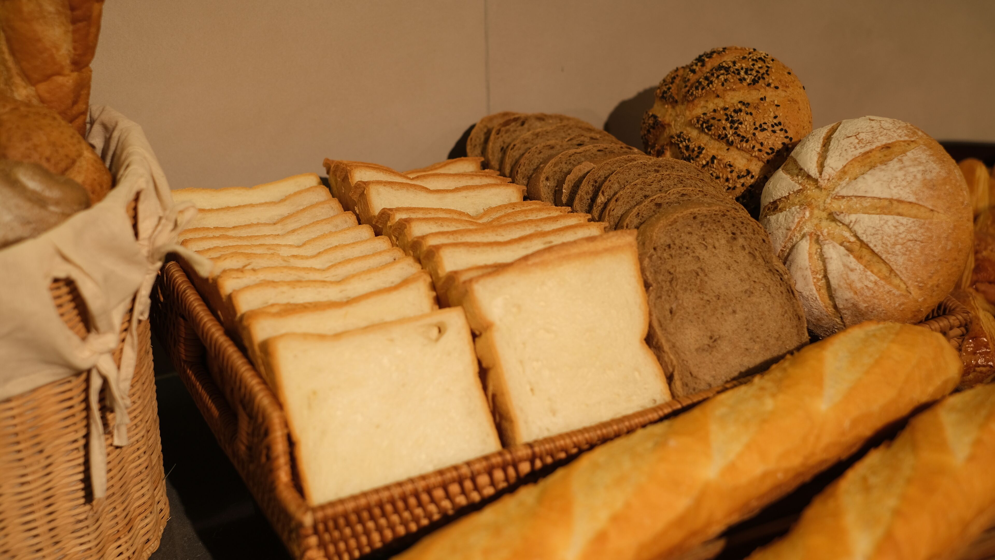 A variety of breads and pastries displayed in wicker baskets.