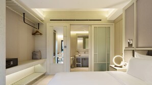 Une chambre d’hôtel moderne avec un lit bien fait, une table de chevet avec une lampe, un miroir et une armoire.
