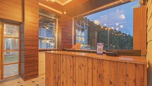 Un mostrador de recepción de madera con vistas a un edificio y árboles a través de un ventanal grande.