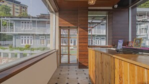 Un área de recepción con mostrador de madera, puerta de cristal que da a un balcón y vistas de edificios residenciales.
