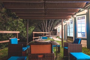 An outdoor patio with wicker furniture and blue cushions, a covered seating area, and a pathway leading to a building.