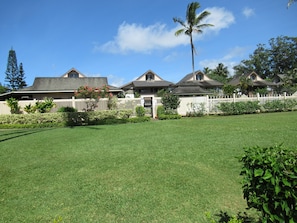 A residential area with houses, a white picket fence, and a well-maintained lawn.
