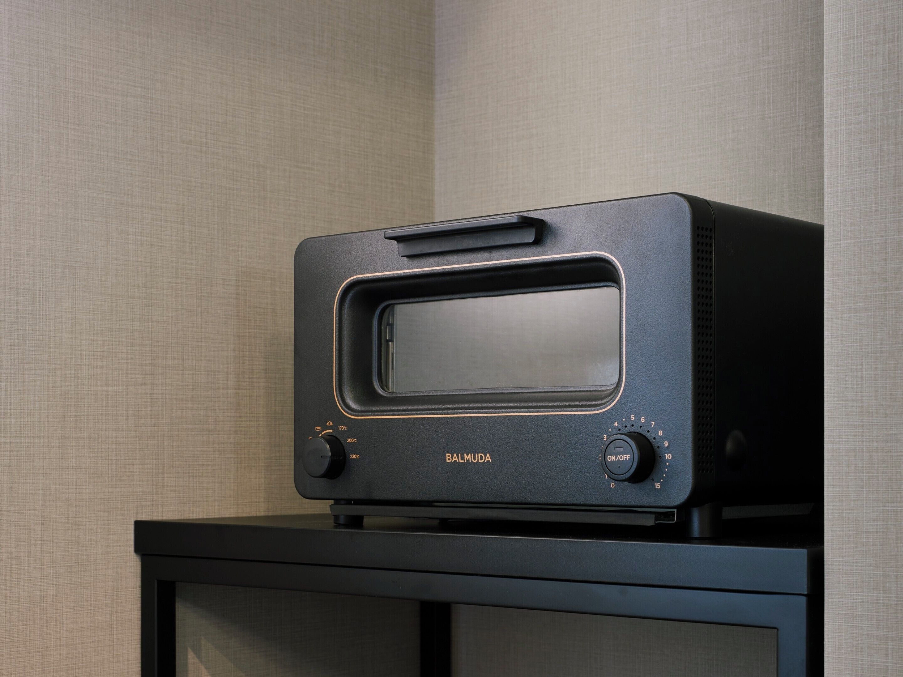 A black portable oven with a digital display and control knobs on a black stand.