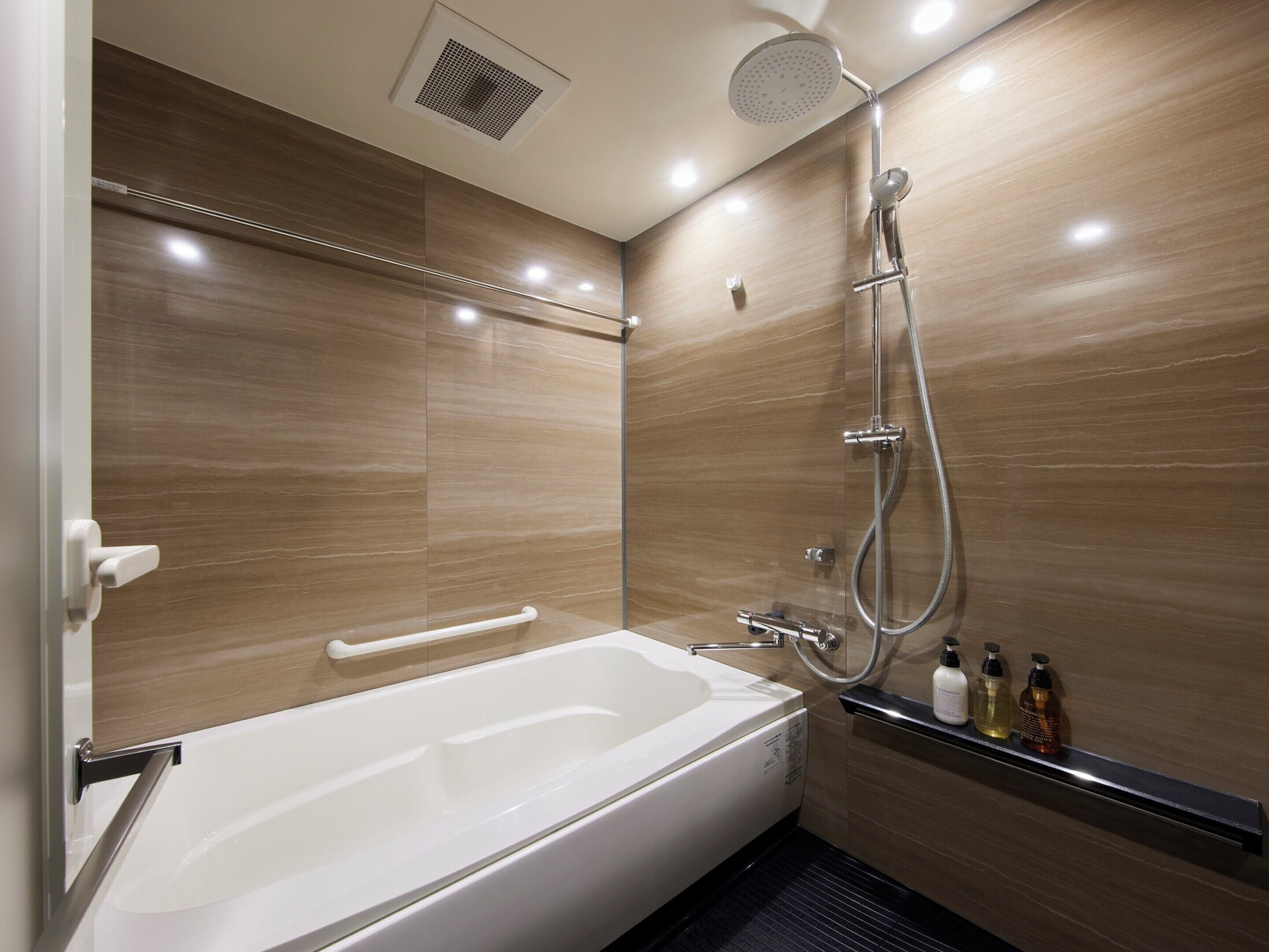 Une salle de bain moderne équipée d’une baignoire, d’une douche et de barres d’appui.