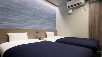 Habitación de hotel con dos camas, un ventanal con vistas, un aire acondicionado y una puerta de madera.