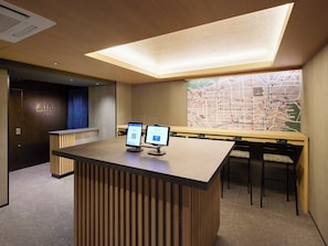 A reception desk with two monitors, a map on the wall, and a wooden reception desk.