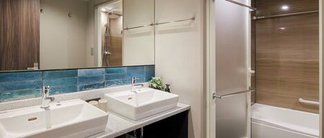 A modern bathroom with two sinks, a large mirror, and a walk-in shower.