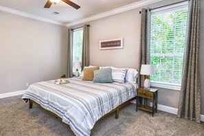 A bedroom with a bed, bedside table, lamp, and a motivational quote on the wall.