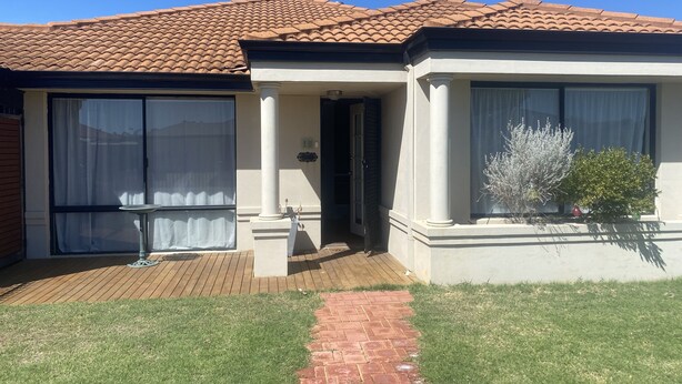 A two-story house with a tiled roof, a covered patio, and a brick pathway leading to the entrance. - Self Contained Unit (Eaton)
