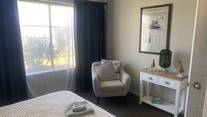 A hotel room with a bed, a chair, a desk, and a window with curtains. - Self Contained Unit (Eaton)