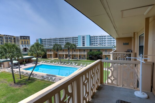 Ein Hotelbalkon mit Pool, Palmen und Blick auf andere Hotelgebäude.