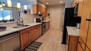 A modern kitchen with wooden cabinets, a stainless steel sink, and a built-in oven. - Spacious Home on a Rushing Glacier Fed Creek (Seward)