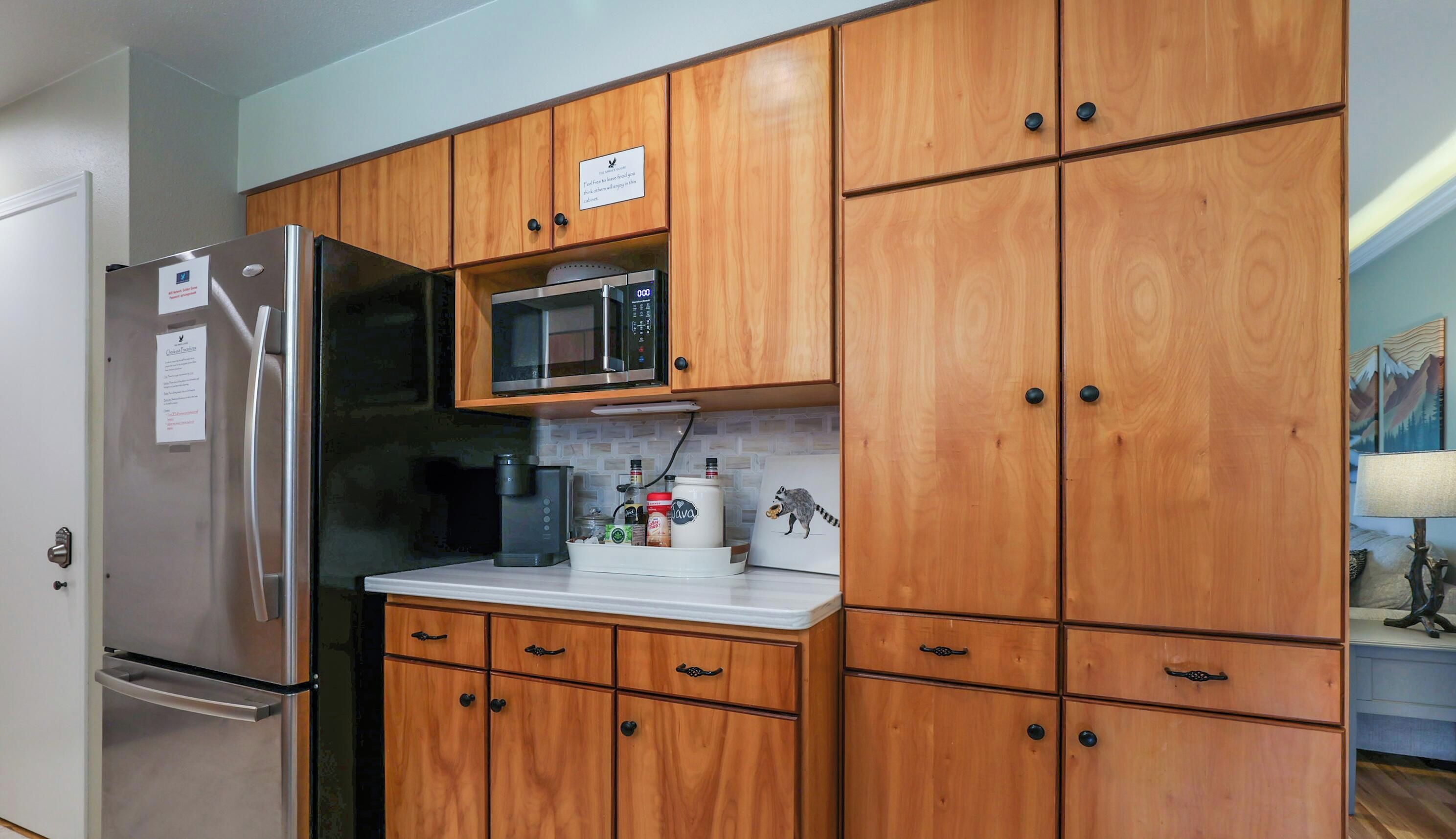 A kitchen with wooden cabinets, a stainless steel refrigerator, a microwave, and a coffee maker.