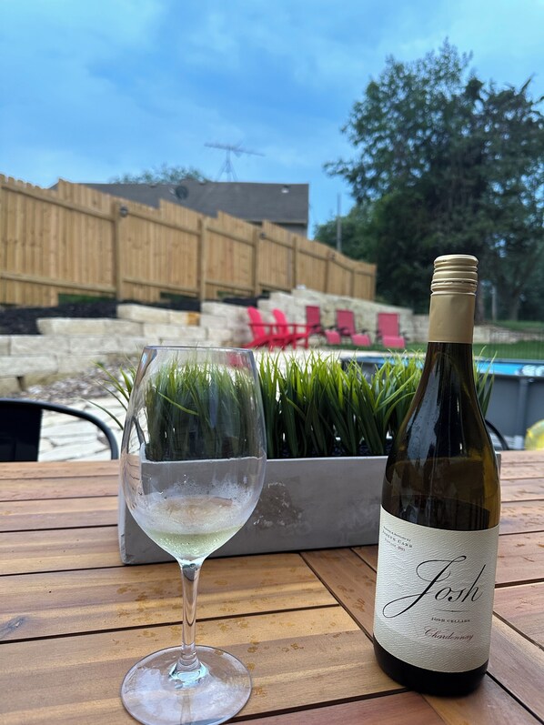Una botella de vino y una copa sobre una mesa de madera al aire libre.