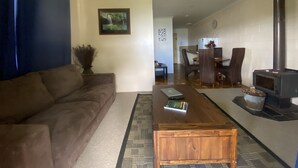 Un salon comprenant un canapé, une table basse en bois, une cheminée et un coin repas avec des chaises et une table.