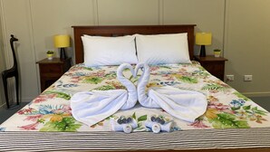 Un lit bien fait, recouvert d’une couvre-lit à motifs floraux, avec deux serviettes assorties et des articles de toilette posés sur le lit.