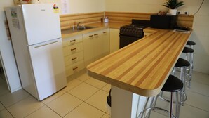 Une cuisine avec un plan de travail en bois, un réfrigérateur, une cuisinière et des tabourets de bar.