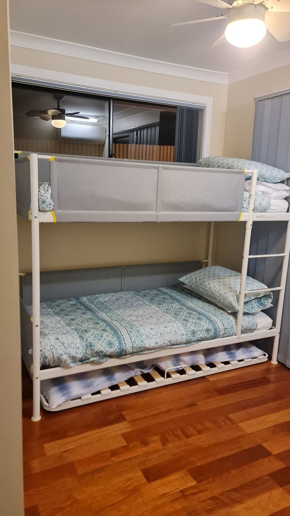 Un lit superposé avec un ventilateur de plafond et une fenêtre avec des rideaux.