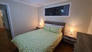 A bedroom with a bed, two bedside tables, a nightstand, a window, and a door. - Private 2 Bedroom Granny Flat. Sleeps 5, Pets Welcome (Darra)