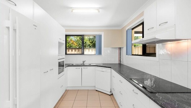 A modern kitchen with white cabinets, a black countertop, and a window with a view of greenery. - Private 2 Bedroom Granny Flat. Sleeps 5, Pets Welcome (Darra)
