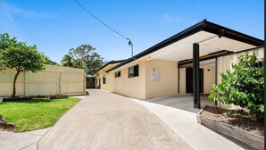 A building with a covered outdoor area, a concrete pathway, and a fenced yard with a tree. - Private 2 Bedroom Granny Flat. Sleeps 5, Pets Welcome (Darra)