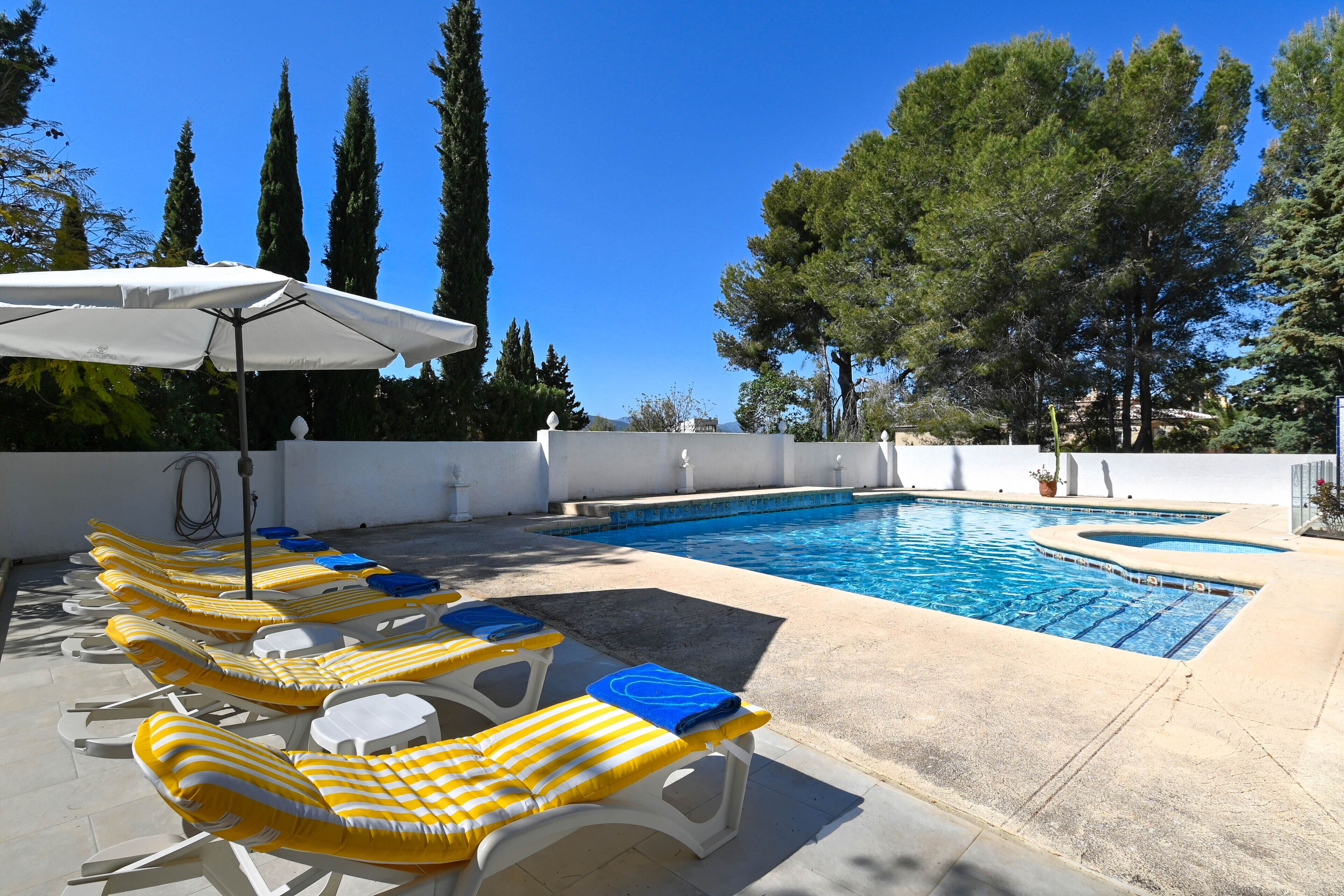 A poolside area with lounge chairs and a white umbrella.