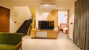 Un salon moderne avec un escalier, un téléviseur à écran plat et un lit en arrière-plan.