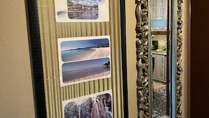 Een muur met een reeks ingelijste foto's van verschillende landschappen en een grote, sierlijke spiegel.