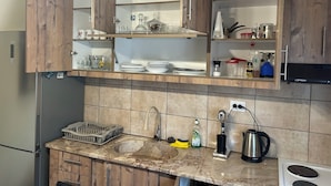 Een keuken met houten kastjes, een roestvrijstalen koelkast, een spoelbak en een fornuis.