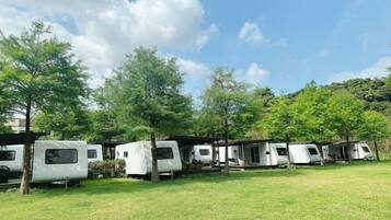 RVs are parked in a serene grassy area surrounded by trees.