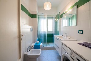 Un baño moderno con ducha, bidé, lavamanos y lavadora.