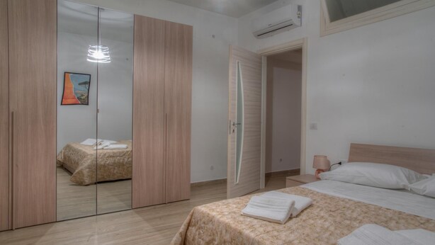 A bedroom with a bed, a nightstand, a mirror, and a wardrobe.