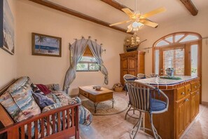 A cozy living room with a sofa, a dining area with chairs, a wooden cabinet, and a ceiling fan.