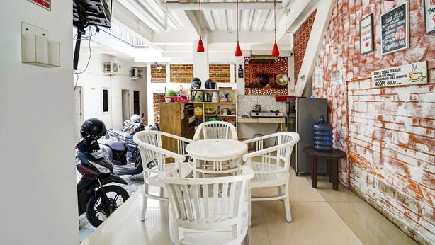 A narrow corridor with a white wall, a red sign, and a motorcycle parked on the left. - Hotel O Guesthouse King Puntodewo (Banguntapan)